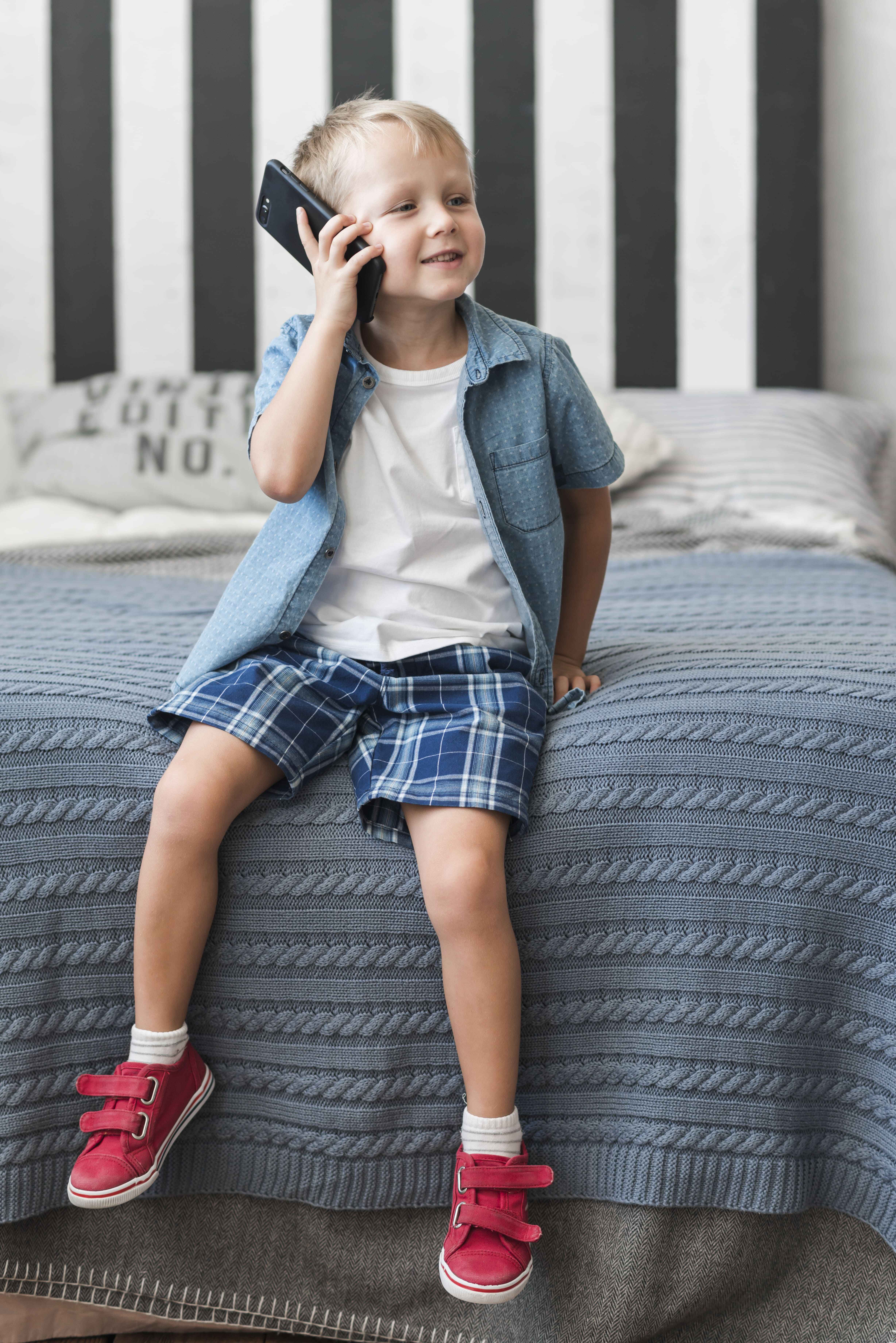 portrait-smiling-boy-sitting-bed-talking-smart-phone (1) (1).jpg